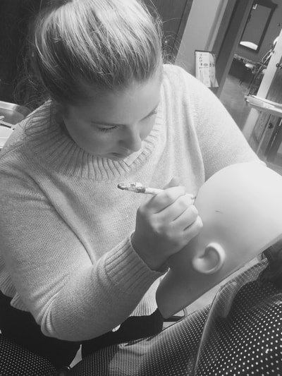 Student practicing eyebrow mapping on mannequin head at The Academy.