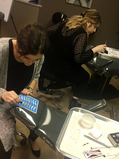 Student practicing hair strokes on practice skins at The Academy.